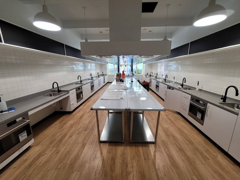 Little Kitchen Academy teaching kitchen with rows of sinks and cooking stations and a central stainless table