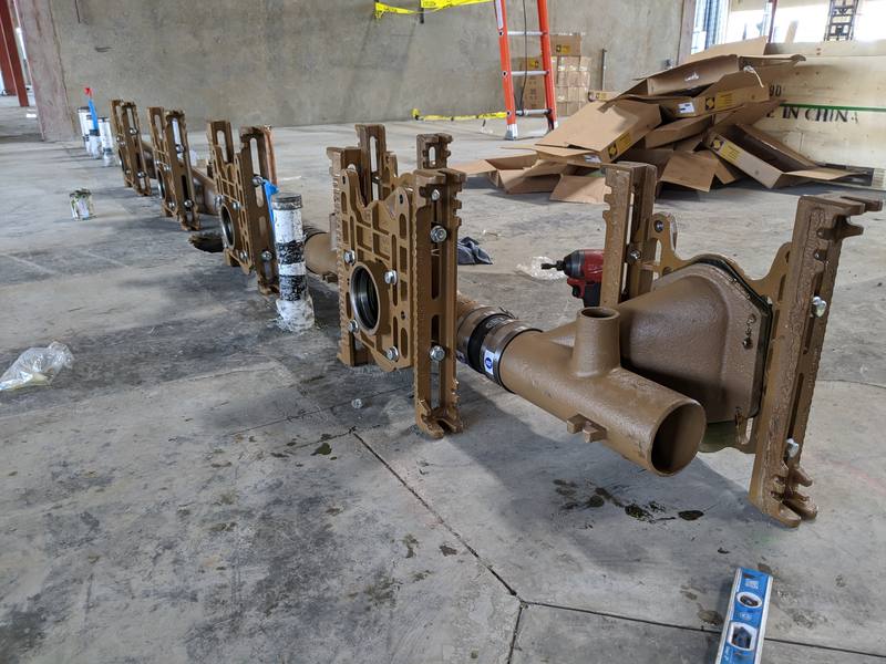 Row of floor drain carriers set on a concrete slab before the walls go up